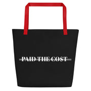 Front view of the black Paid The Cost Large Tote Bag with red handle. 