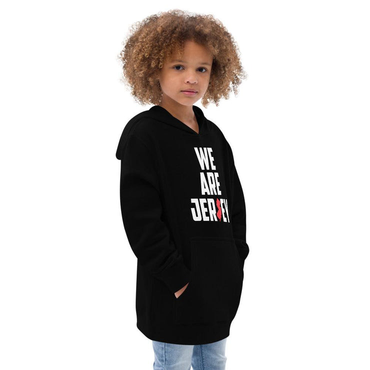 Side view of a female child wearing the black We Are Jersey Kids Hoodie.